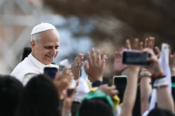 Un religieux en tenue blanche salue la foule lors d'une apparition publique.