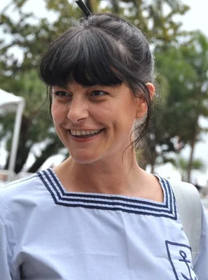 Lio arborant un look marin classique et un large sourire.