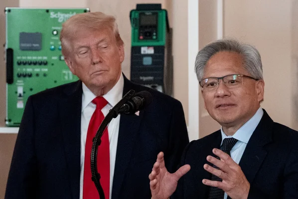 Donald Trump et Jensen Huang discutant lors d'une rencontre à un podium avec une installation industrielle en fond.