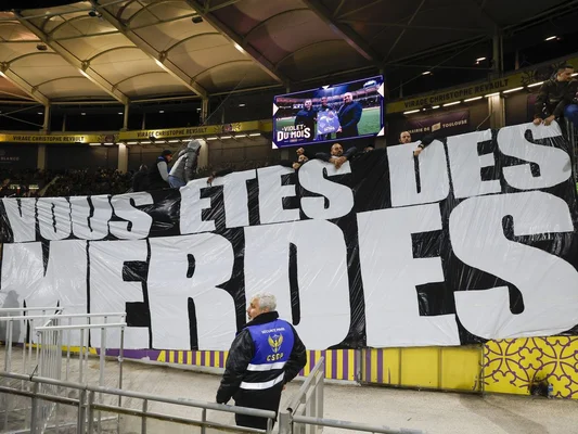 Supporters tenant une banderole hostile au milieu du stade.