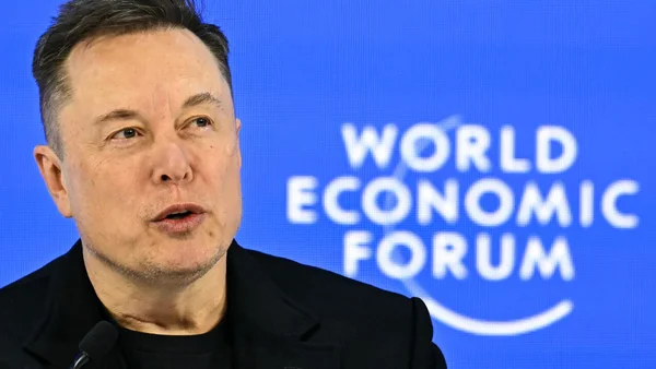 Elon Musk devant un panneau 'WORLD ECONOMIC FORUM'.