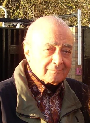 Portrait de Mohamed Al-Fayed portant une veste verte et une chemise à motifs.