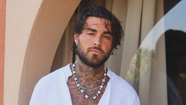 Thibault Garcia aux côtés de sa nouvelle conquête blonde, dans une tenue à imprimé, sous un éclairage chaleureux.