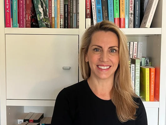 Une femme devant une bibliothèque chargée de livres, illustrant l'univers littéraire du Pacte des Héritières.