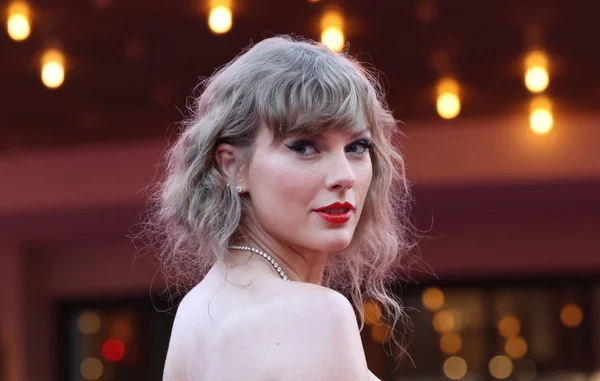 Taylor Swift portant une robe bleue scintillante et des bijoux imposants.