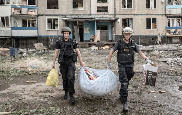 Militaires transportant du matériel devant un immeuble ravagé par les combats.