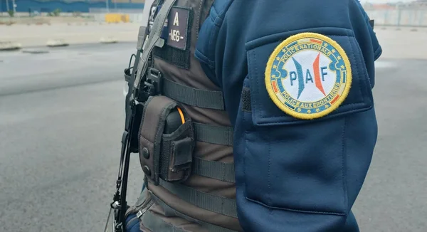Un policier aux frontières en uniforme bleu tenant une arme.