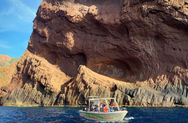 Un bateau touristique naviguant devant les parois rocheuses de la réserve de Scandola.