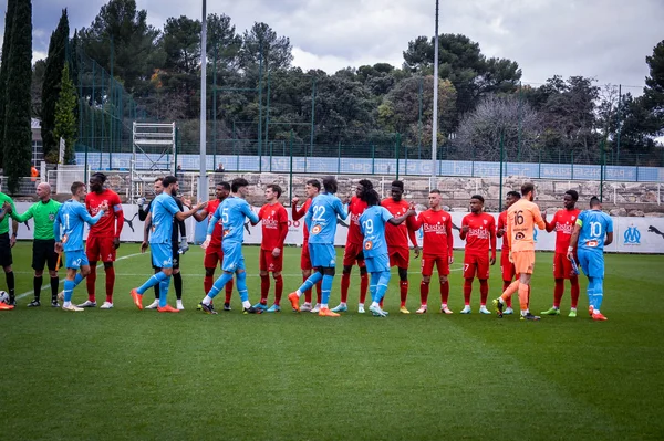 Joueurs de l'OM et du Nîmes Olympique se serrant la main lors d'un match amical à La Commanderie le 19 décembre 2022.