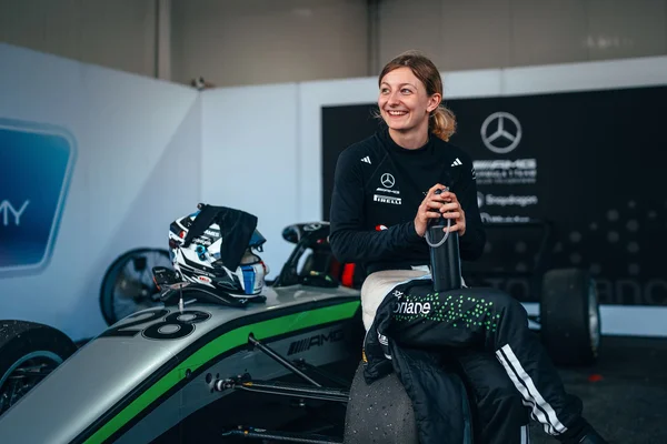 Doriane Pin posant sur son véhicule de course avec l'écurie Mercedes.