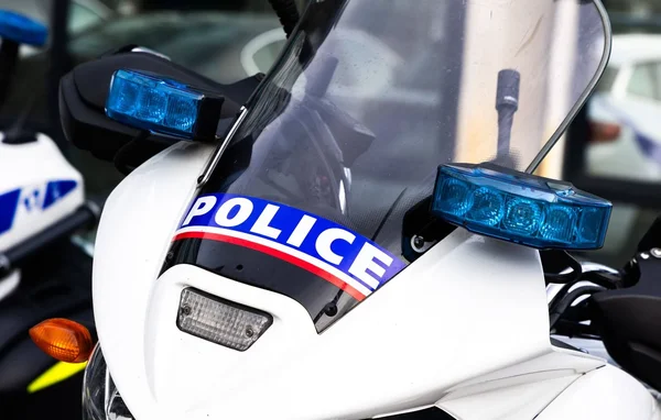 Avant d'une moto de police avec l'inscription POLICE et des gyrophares bleus.