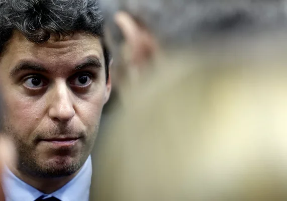 Gabriel Attal affiche un air sérieux face aux caméras.