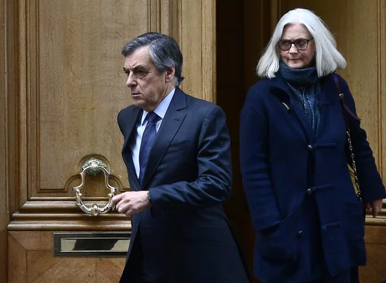 Robert Bourgi et une femme posant devant une porte en bois.