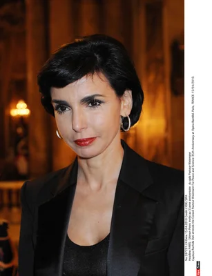 Rachida Dati en tenue noire dans un intérieur aux détails architecturaux.