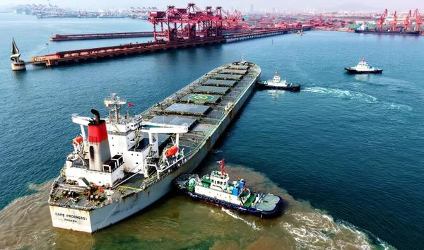 Navire cargo dans un port avec grues et infrastructure industrielle.