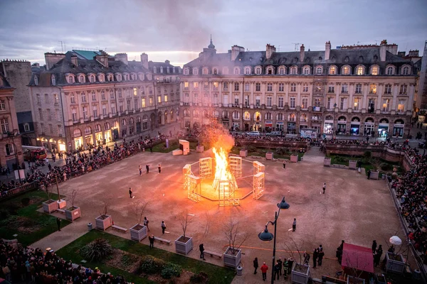 Installation pyrotechnique sur une place rennaise lors d'un événement au crépuscule.