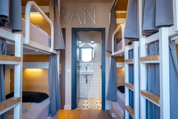 Intérieur d'une auberge de jeunesse à Barcelone avec des lits superposés et une salle de bain attenante.