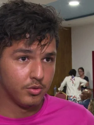 Portrait de Mehdi Kessaci vêtu d'une chemise rose.