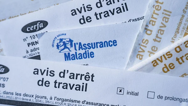 Documents administratifs empilés dont un papier de l'Assurance Maladie au premier plan.
