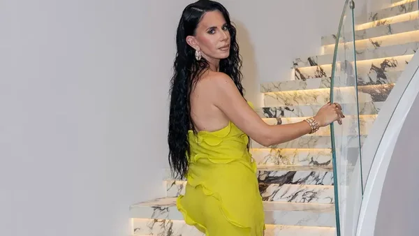 Aurélie B. posant dans une robe jaune sur un escalier en marbre.
