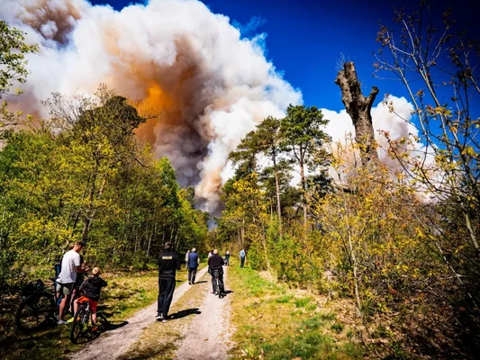 Des riverains observant la fumée d'un incendie sur un terrain militaire aux Pays-Bas.