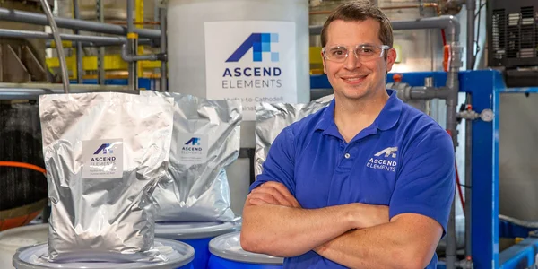 Employé d'Ascend Elements posant devant des sacs de matériaux.