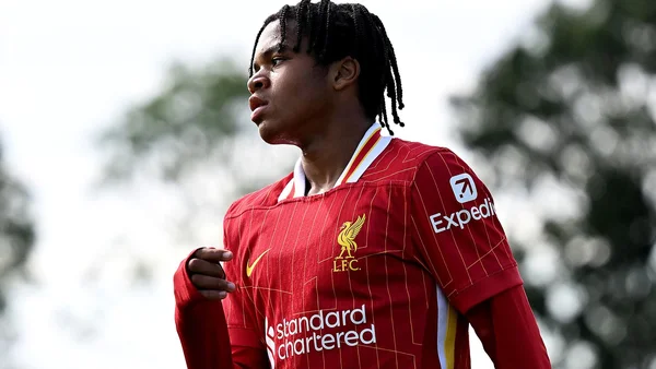 Rio Ngumoha portant le maillot rouge de Liverpool FC, debout en extérieur.