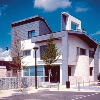 Un bâtiment moderne caractérisé par ses lignes angulaires et ses grandes fenêtres sous un ciel bleu.