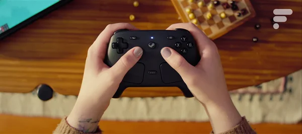 Le Steam Controller de Valve tenu en main au-dessus d'un plateau de jeu.