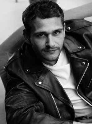 Ulysse Josselin en veste de cuir et col roulé blanc.