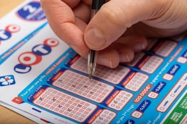 Un joueur coche des numéros sur une grille officielle du jeu Loto.