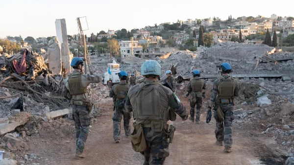 Soldats de la Finul évoluant au milieu des décombres dans une localité libanaise sinistrée, avec un véhicule onusien en arrière-plan.