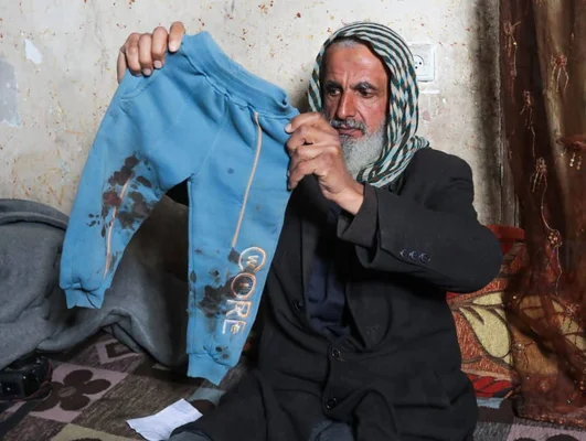 Un membre de la famille Abu Nassar exhibant le pantalon du bambin pour montrer les traces présumées de torture lors de la détention à Gaza.