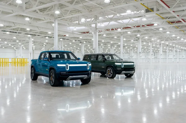 Deux modèles Rivian, un bleu et un vert, dans un entrepôt industriel.