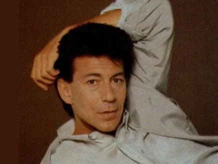 François Feldman, chanteur des années 80, posant en chemise claire.