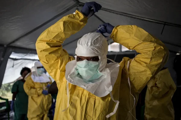 Un agent de santé en tenue de protection ajuste son équipement avant une intervention contre Ebola.