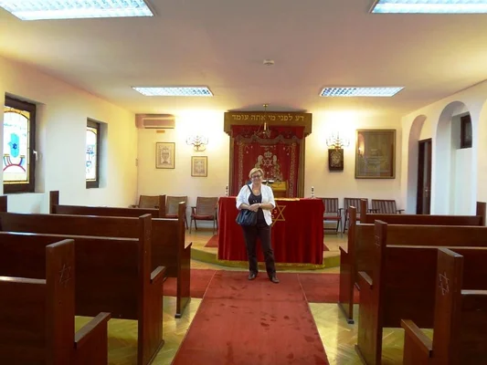 Intérieur de la synagogue de Skopje, montrant les bancs en bois et le rideau sacré.