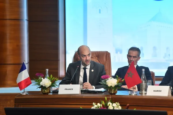 Réunion diplomatique franco-marocaine avec drapeaux et plaques nominatives.