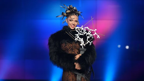 La gagnante de l'Eurovision 2026 posant avec son trophée et une coiffe à plumes.