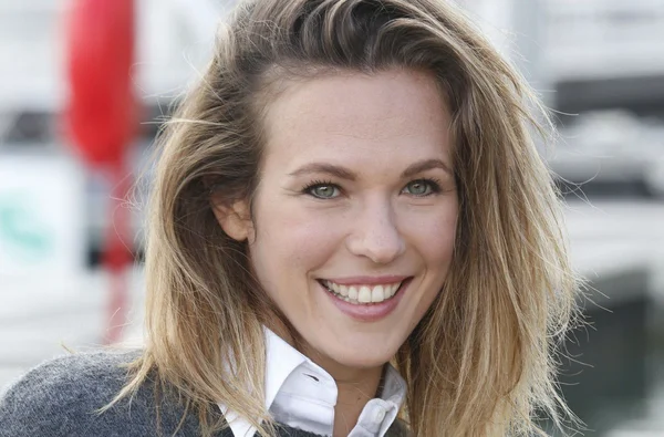Lorie, souriante, en chemise blanche et pull gris.