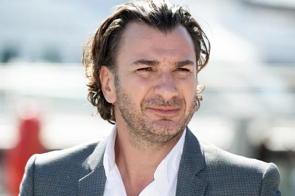 Michaël Youn en chemise blanche et blazer gris.