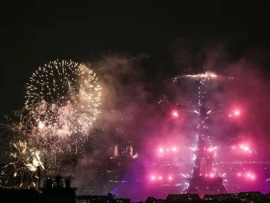 Feu d'artifice parisien avec la Tour Eiffel illuminée en rose et violet.