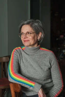 Sandrine Rousseau dans un portrait décontracté avec un pull arc-en-ciel.