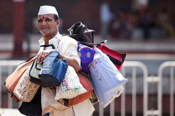 Un dabbawala transportant des bagages, symbole de la force et de l'endurance des livreurs de repas de Mumbai.