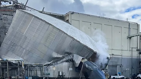 Réservoir effondré contre une usine, avec de la vapeur blanche s'échappant, après l'explosion à l'usine de pâte à papier de Longview.