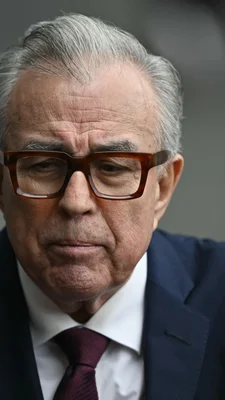 Gros plan de Ruben Rocha Moya, homme aux cheveux gris et lunettes à monture marron, portant une chemise blanche et une cravate sombre.