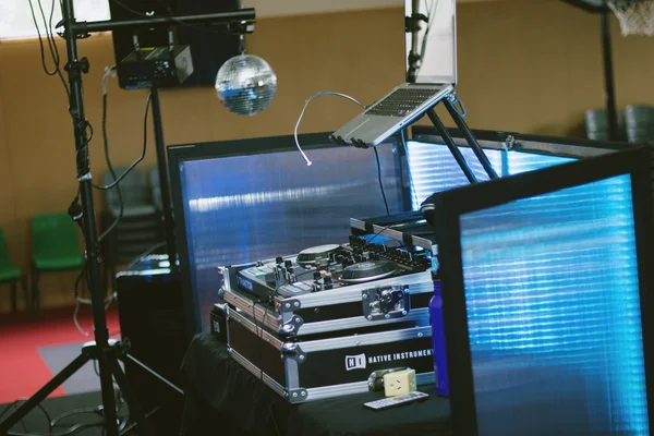 Un poste DJ équipé d'un contrôleur Native Instruments Traktor Kontrol S4 et d'un ordinateur portable, avec éclairage LED bleu et boule disco.