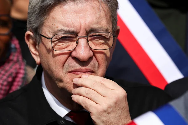 Jean-Luc Mélenchon, à un pas d'une quatrième candidature à la présidentielle, drapeau tricolore en fond.