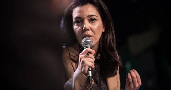 Sophia Chikirou s'exprimant au micro, manteau beige.