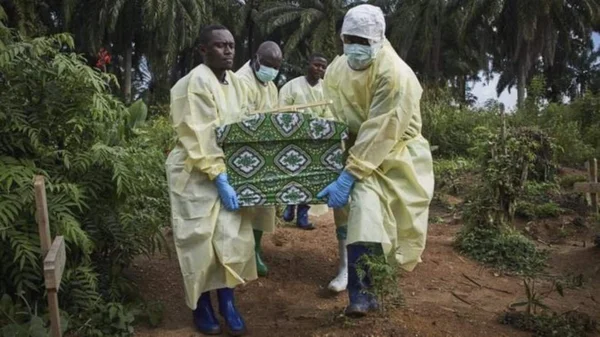 Des agents de santé en tenue de protection transportent un cercueil lors d'une inhumation liée à Ebola dans l'est de la RDC.